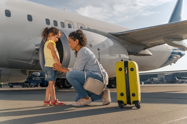 Frau und Kind warten auf Flug in der Nähe von weißem Flugzeug