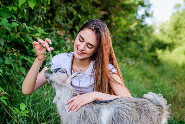 Frau und kleine Ziege grünes Gras Tierarzt Beruf Öko-Bauernhof Liebe und Fürsorge Tierrecht Bauernhof- und Landwirtschaftskonzept Dorftiere Mädchen spielen niedliche Ziege Tier füttern Tiere schützen