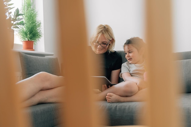Frau und Mädchen benutzen zu Hause ein digitales Tablet
