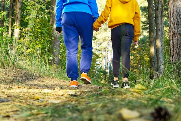 Frau und Mädchen, die den Waldweg am sonnigen Tag wandern