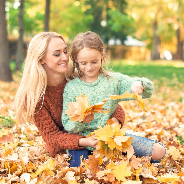 Frau und Mädchen, die herbstgelbe Blätter halten