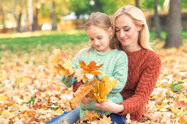 Frau und Mädchen, die herbstgelbe Blätter halten