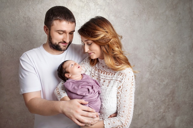 Frau und Mann, die ein Neugeborenes halten. Mama, Papa und Baby. Porträt der lächelnden Familie mit neugeborenem auf den Händen. copyspace