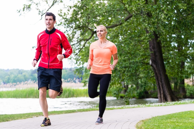 Frau und Mann, die zusammen auf Feldweg im Wald joggen