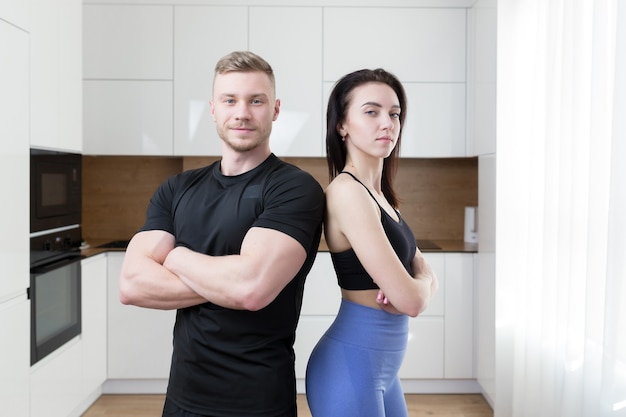 Frau und Mann posieren an der Kamera, zwei Fitnessathleten in der Küche zu Hause