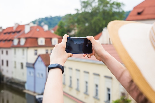 Frau unter Bild der Altstadt in Prag mit einem Smartphone.