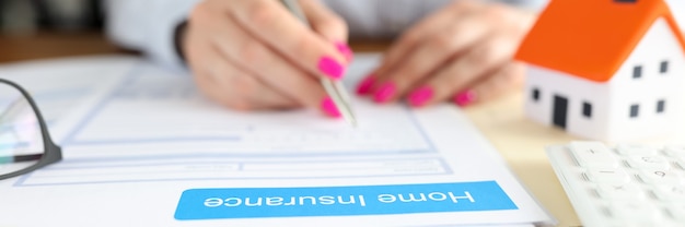 Frau unterschreibt Dokumente des Hausratversicherungsvertrags