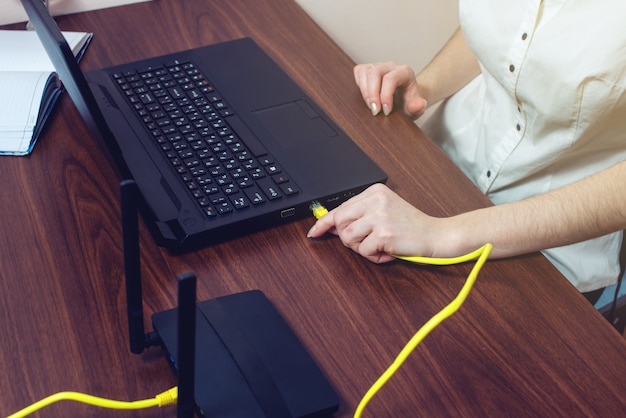 Frau verbinden Internetkabel zum Anschluss am Laptop