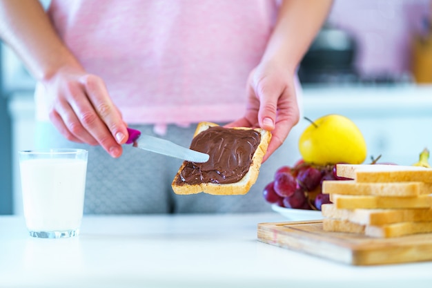 Frau verbreitet Nussschokoladencreme auf Toastbrot für ein Dessert zu Hause