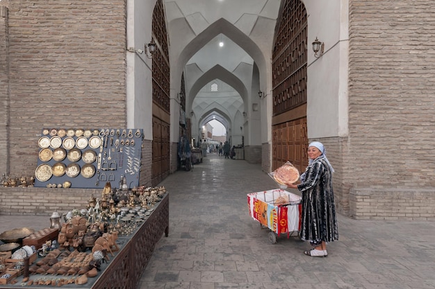 Frau verkauft usbekisches traditionelles Brot am Eingang zum überdachten Markt in der Altstadt von Buchara Usbekistan