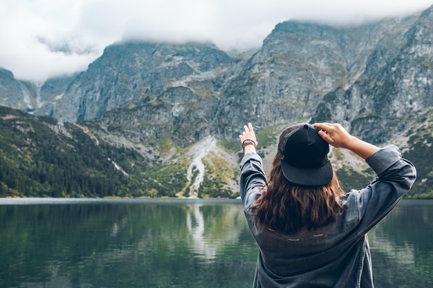 Foto frau versucht, den himmel zu erreichen landschaft blick auf den see in den bergen