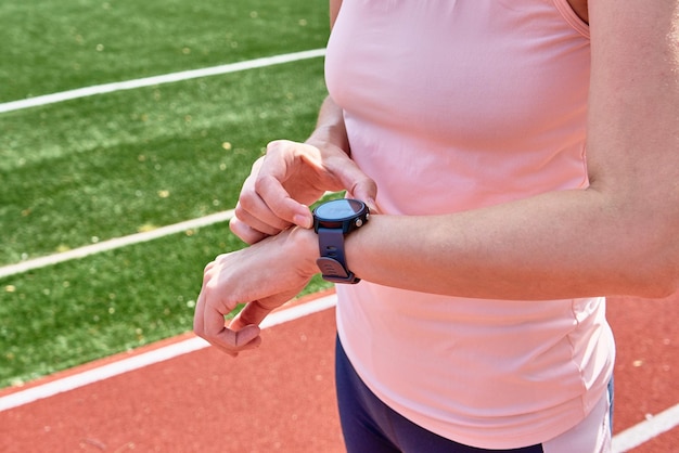 Frau verwendet Fitnessuhr vor Cardio-Übungen, um Ergebnisse auf Smartwatch nach dem Training zu überprüfen