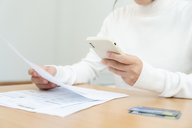 Frau verwendet Telefon-Scan-Barcode oder QR-Codes, um Kreditkartenrechnung zu bezahlen, nachdem sie das Dokument, die Rechnungszahlung, erhalten hat, erhält Strom, digitale Zahlungstechnologie, die Finanztransaktionen scannt