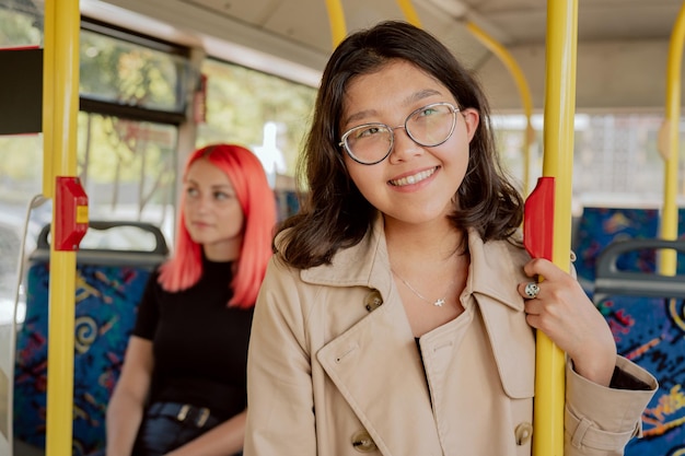 Frau von koreanischer asiatischer Schönheit mit Brille und Trenchcoat ist mit öffentlichen Verkehrsmitteln unterwegs