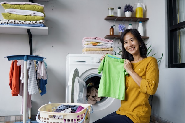 Frau vor der Waschmaschine, die einige Wäsche macht, die Kleidung nach innen lädt