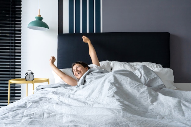 Frau wacht gut gelaunt in einer stilvollen Wohnung auf. Dehnt sich mit einem Lächeln aus, das den Tag beginnt