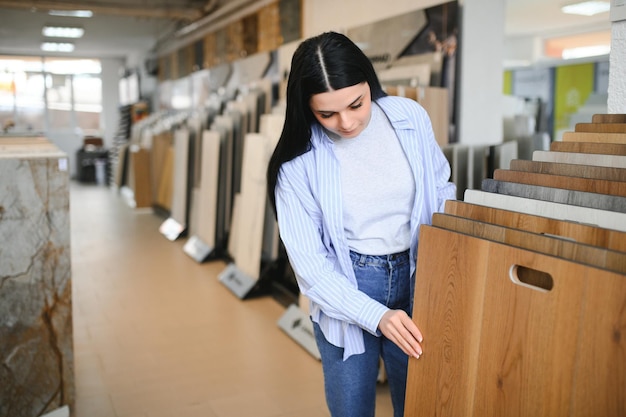 Frau wählt aus Proben in einem Bodenbelag-Laden ein Laminatboden-Design aus