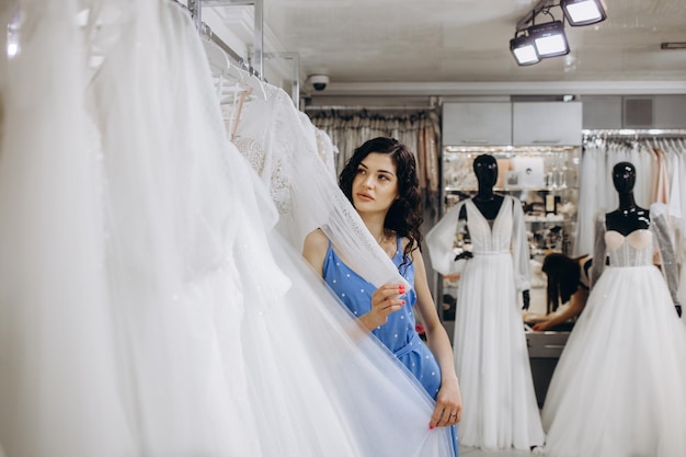 Frau wählt Hochzeitskleid im Shop