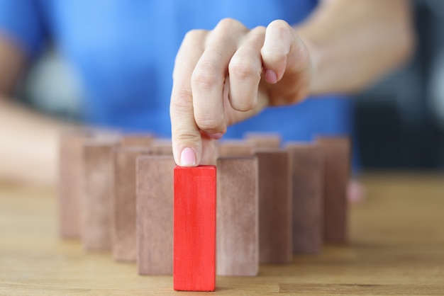 Frau wählt roten Holzblock unter anderem auf Holztisch und trifft richtiges Entscheidungskonzept