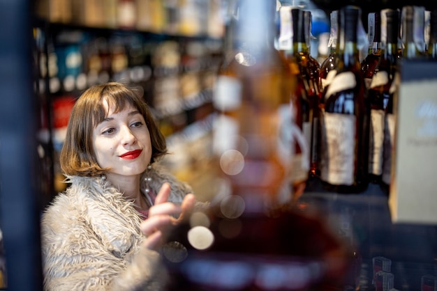 Foto frau wählt starken alkohol im supermarkt