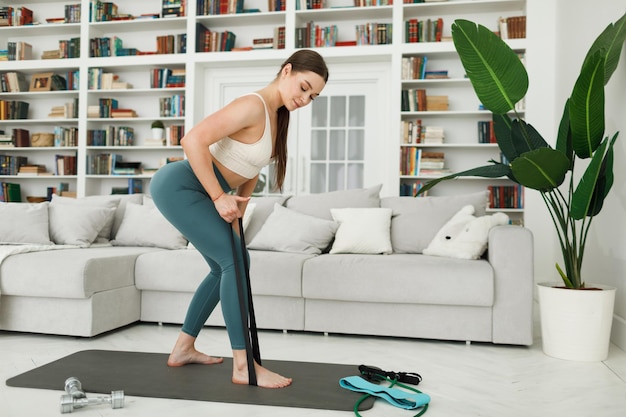 Foto frau während ihres fitness-trainings zu hause mit gummi-widerstandsband