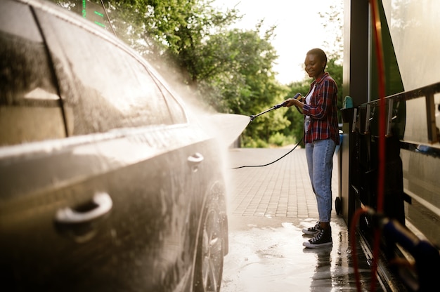 Frau wäscht Schaum vom Auto ab, Autowäsche von Hand