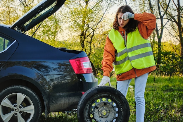 Frau wechselt das beschädigte Rad des Autos