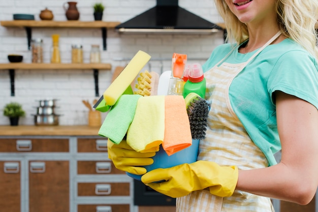 Foto frau, welche die gelben gummihandschuhe zu hause halten reinigungsprodukte trägt