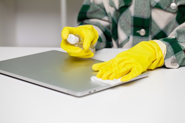 Frau wischt Laptop vom Staub im Büro am Tisch ab