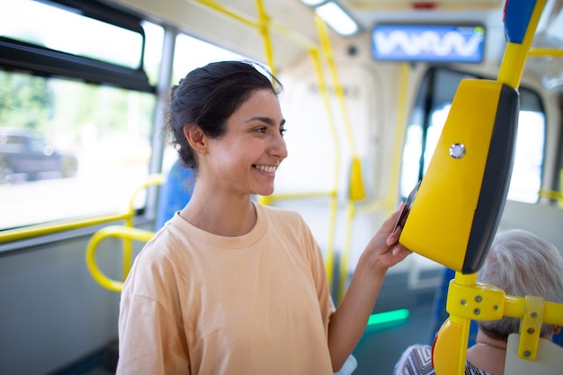 Frau zahlt kontaktlos mit Smartphone für die öffentlichen Verkehrsmittel in der Straßenbahn