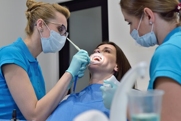 Frau Zahnarzt und Assistent untersuchen Patienten