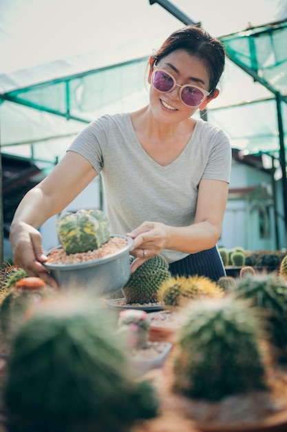 Frau zahnig lächelnd mit Kaktustopf in der Hand