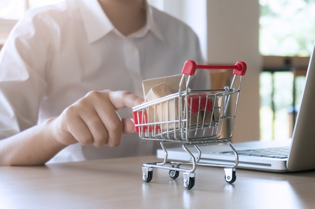 Frau Zeigefinger drückt kleinen Warenkorb mit Internet Online-Shopping-Konzept.