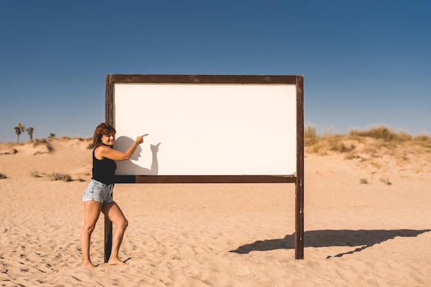 Frau zeigt auf ein Schild am Strand