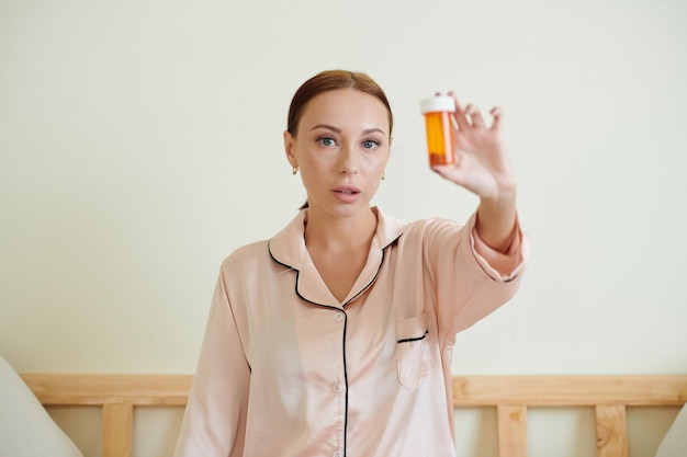 Frau zeigt Behälter mit verschriebener Medizin