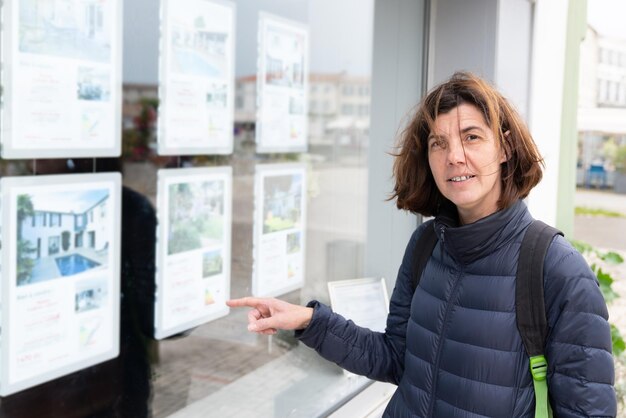 Foto frau zeigt mit dem finger auf die vorderseite der immobilienagentur