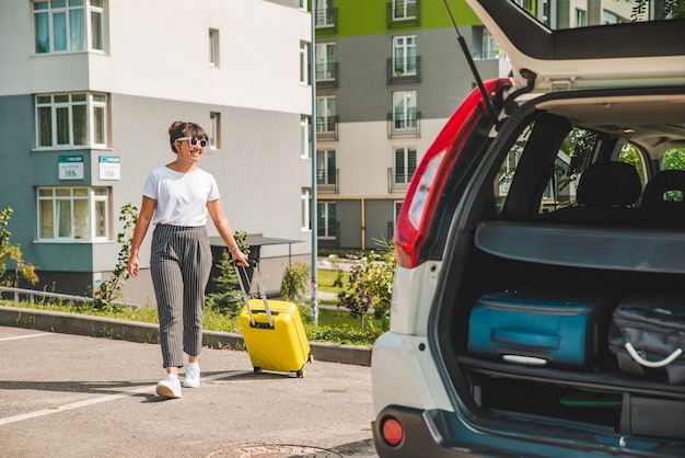 Frau zieht Koffer auf Rädern zur Autoreise