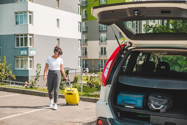 Frau zieht Koffer auf Rädern zur Autoreise