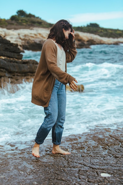 Frau zu Fuß am felsigen Strand in nassen Jeans barfuß Sommerurlaub am Meer
