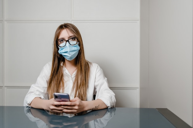 Frau zu Hause Büro tragen Maske und mit Telefon