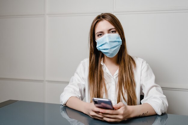 Frau zu Hause Büro tragen Maske und mit Telefon