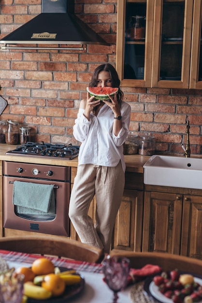 Frau zu Hause isst Wassermelone in der Küche