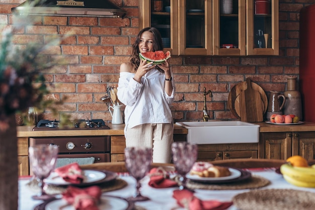 Frau zu Hause isst Wassermelone in der Küche