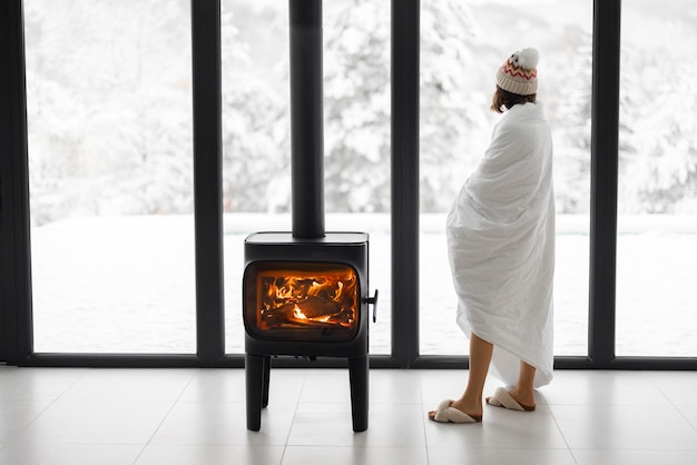 Frau zu Hause mit brennendem Kamin im Winter auf Natur