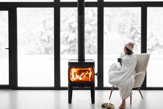 Frau zu Hause mit brennendem Kamin im Winter auf Natur