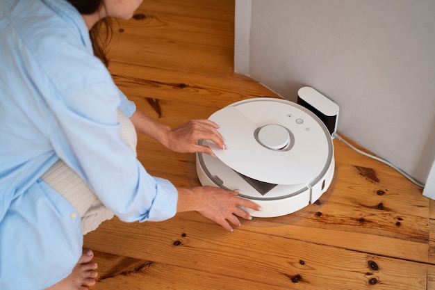 Foto frau zu hause mit kabellosem roboterstaubsauger