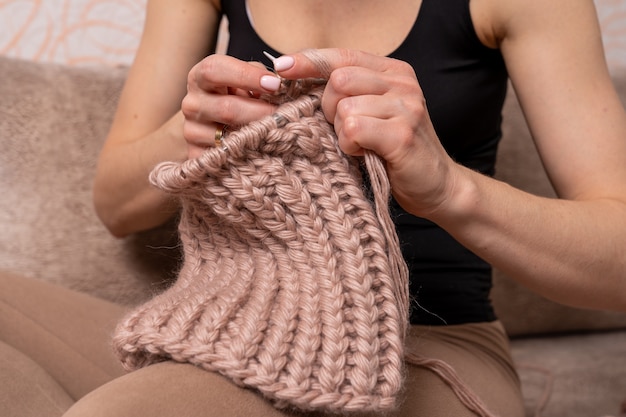 Frau zu Hause strickt ein Produkt aus Wollfaden