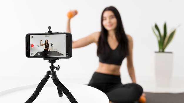 Frau zu Hause vlogging während des Trainings mit Smartphone