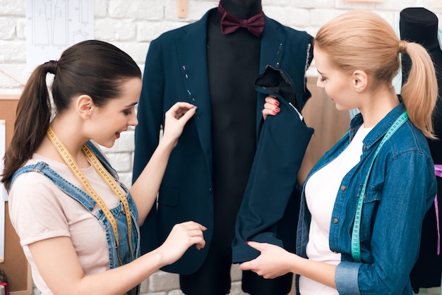 Frauen an der Kleiderfabrik, die neue Mannanzugsjacke desining ist.