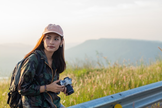 Frauen asiatisch mit rucksack, der ein foto auf ansicht am sonnenaufgang-berggipfel des meeres macht